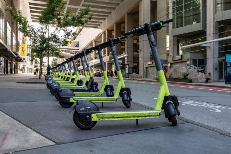 Una fila de patinetes eléctricos estacionados en una acera urbana.