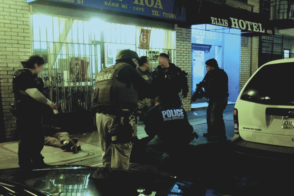 Agentes de policía detienen a un sospechoso frente a un edificio comercial.