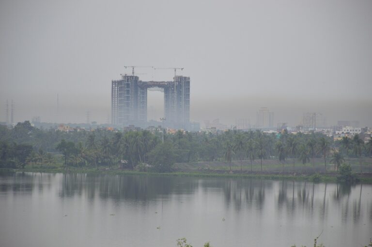Paisaje urbano brumoso sobre un cuerpo de agua, con edificios visibles a través de la neblina.