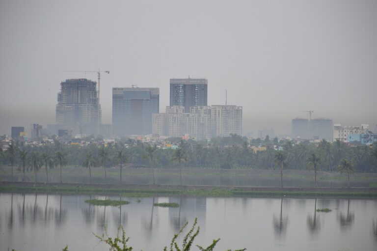 Vista de un horizonte urbano brumoso sobre un cuerpo de agua, indicando contaminación atmosférica.