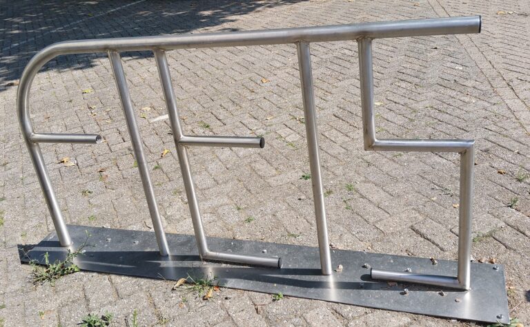 Barandilla metálica de acceso a escaleras en un área pavimentada.