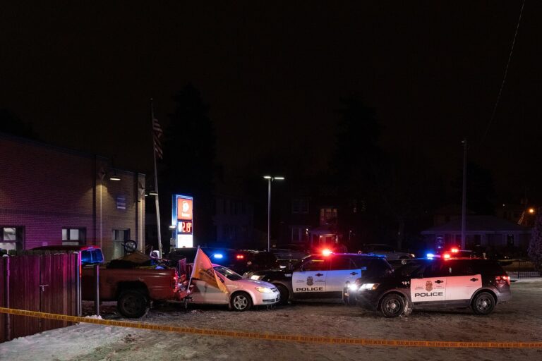 Vehículos policiales iluminando una escena en la noche, sugiriendo una investigación policial.