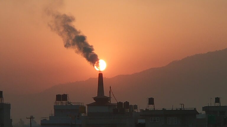 Humo de fábrica elevándose al atardecer sobre la ciudad de Santiago.