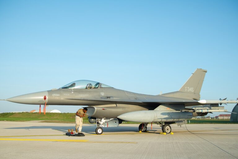 Un avión de combate F-16C Fighting Falcon estacionado en una pista de aeropuerto bajo un cielo azul despejado.