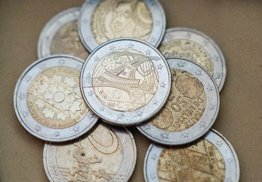 Varias monedas conmemorativas de diferentes países y eventos, apiladas sobre una superficie neutra.