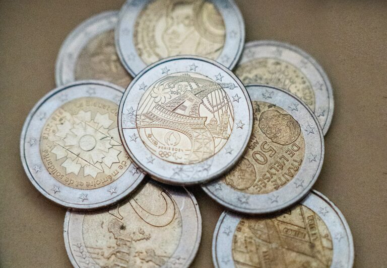 Varias monedas conmemorativas de diferentes países y eventos, apiladas sobre una superficie neutra.