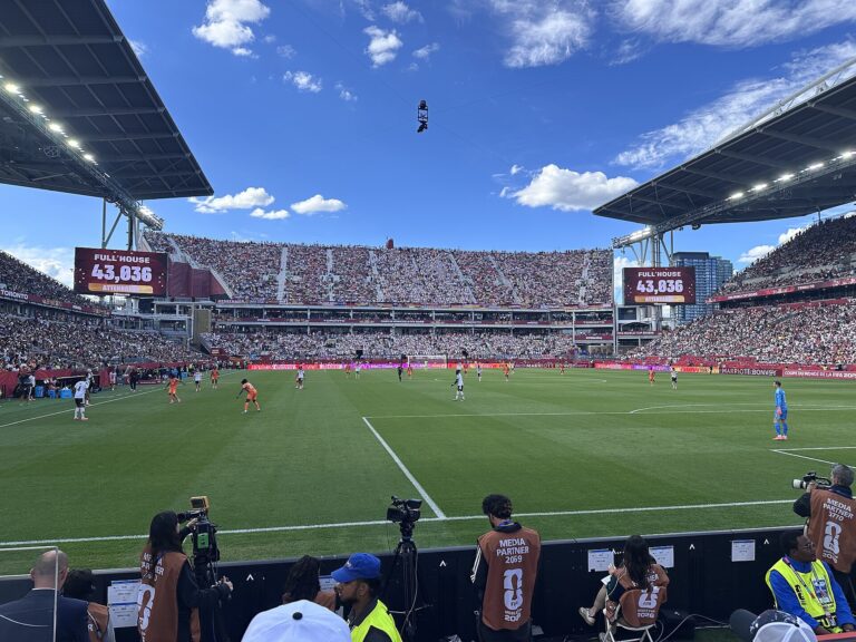 Vista panorámica de un estadio de fútbol lleno con el césped en primer plano, listo para un partido de la Copa Mundial 2026.