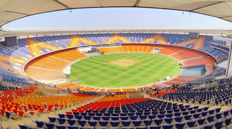 Vista panorámica de un estadio de fútbol grande con gradas llenas y un campo de juego verde.