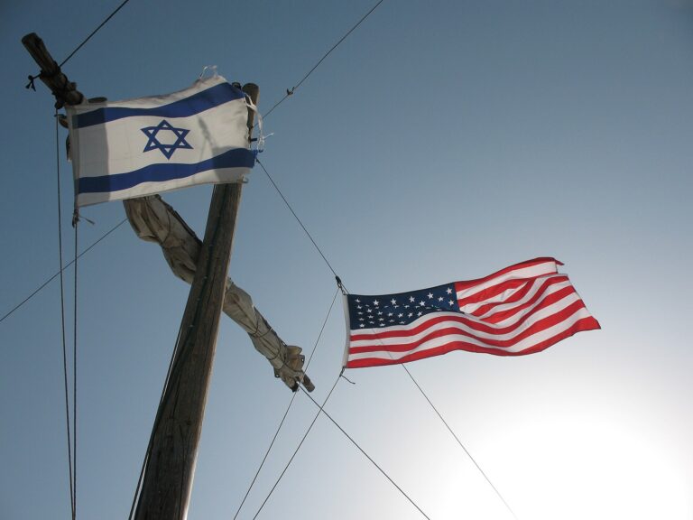 Bandera de Israel y bandera de Estados Unidos ondeadas en un poste de madera.