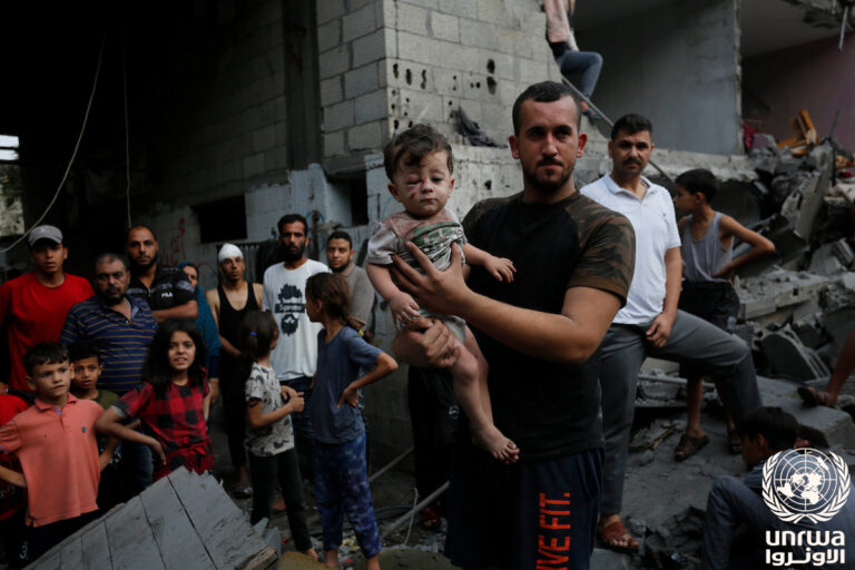 Un hombre sostiene a un niño en un entorno de escombros en Gaza.