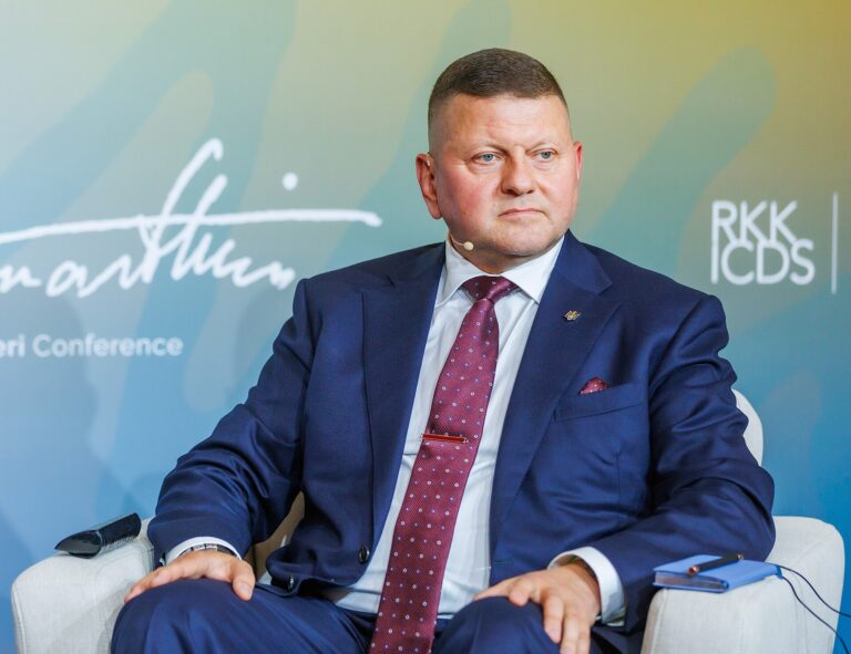 Valerii Zaluzhnyi sentado en un evento, vistiendo un traje azul oscuro y corbata estampada.