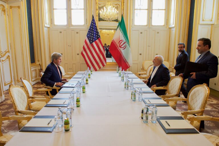 Delegados de EE. UU. e Irán en una mesa de negociación en un salón elegante.