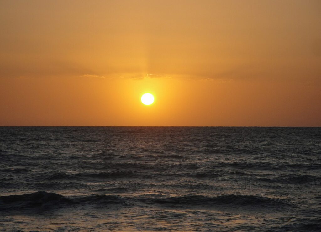 Atardecer sobre el mar, mostrando el horizonte y el sol bajo.
