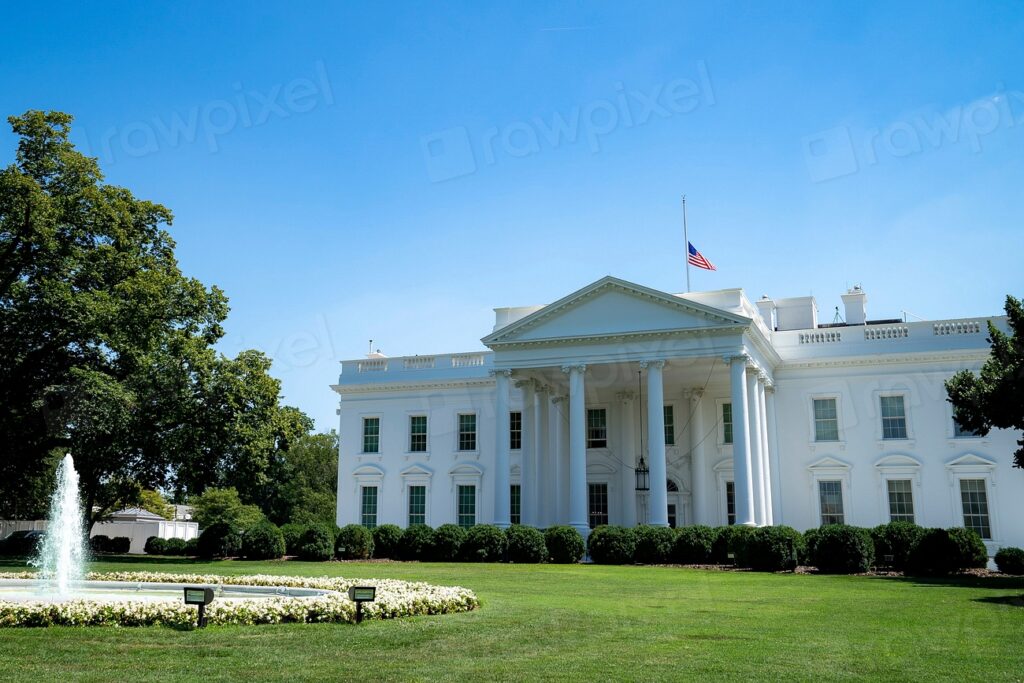 Vista exterior de la Casa Blanca de EE. UU. con el cielo azul y césped verde.