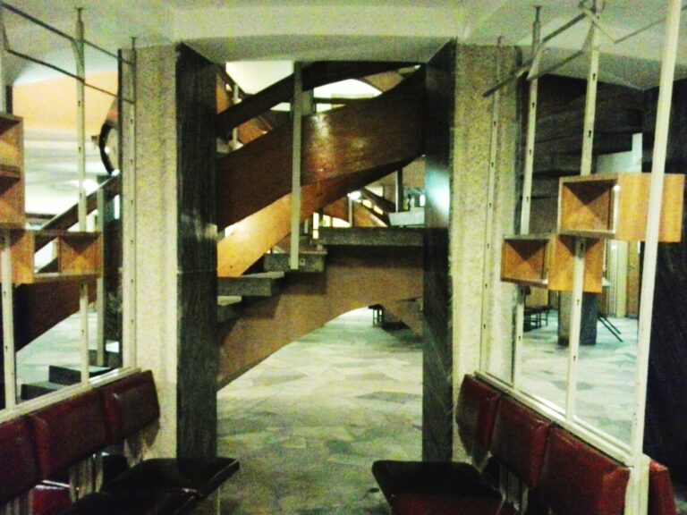 Interior moderno de un hospital con una gran escalera de caracol y columnas visibles.