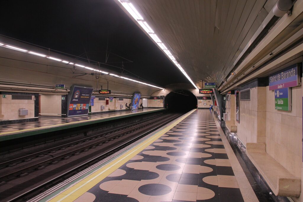 Vista del andén de la estación de Sainz de Baranda, Madrid, con vías de tren y señalización.