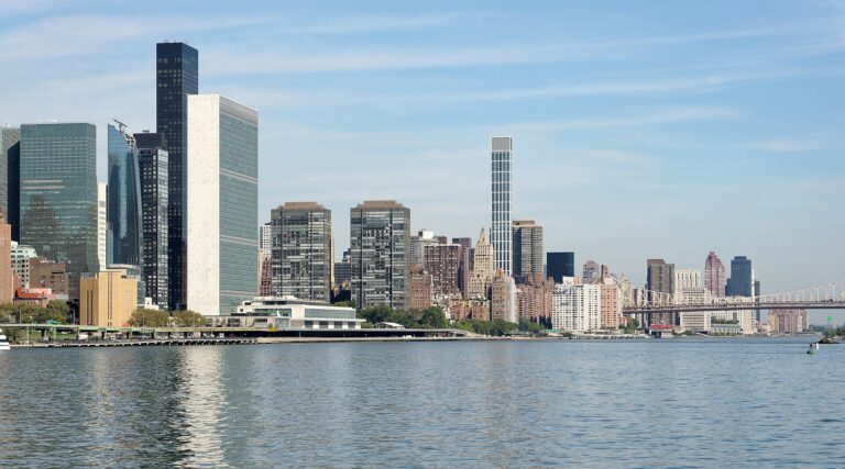 Vista del horizonte de la ciudad con edificios modernos y un río en primer plano.