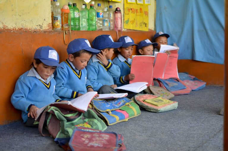 Un grupo de niños en un aula, sentados en el suelo con libros y materiales de estudio.