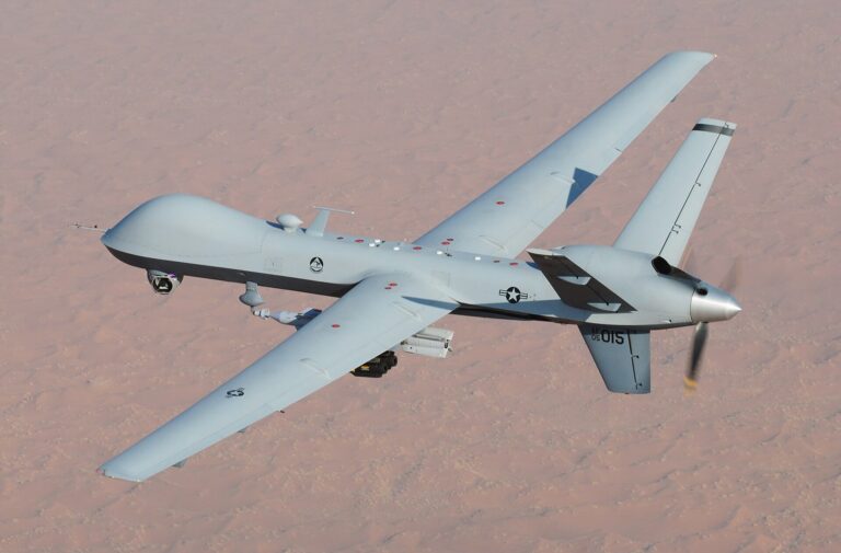 Un vehículo aéreo no tripulado (UAV) militar vuela sobre un paisaje desértico.