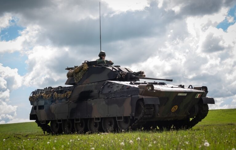 Vehículo blindado militar en un campo abierto bajo un cielo nublado.