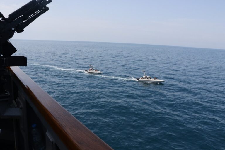 Varias embarcaciones navales en alta mar, con un barco más grande y otros más pequeños en formación.