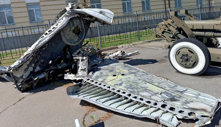 Restos de un vehículo militar, posiblemente un avión o tanque, en un área exterior.